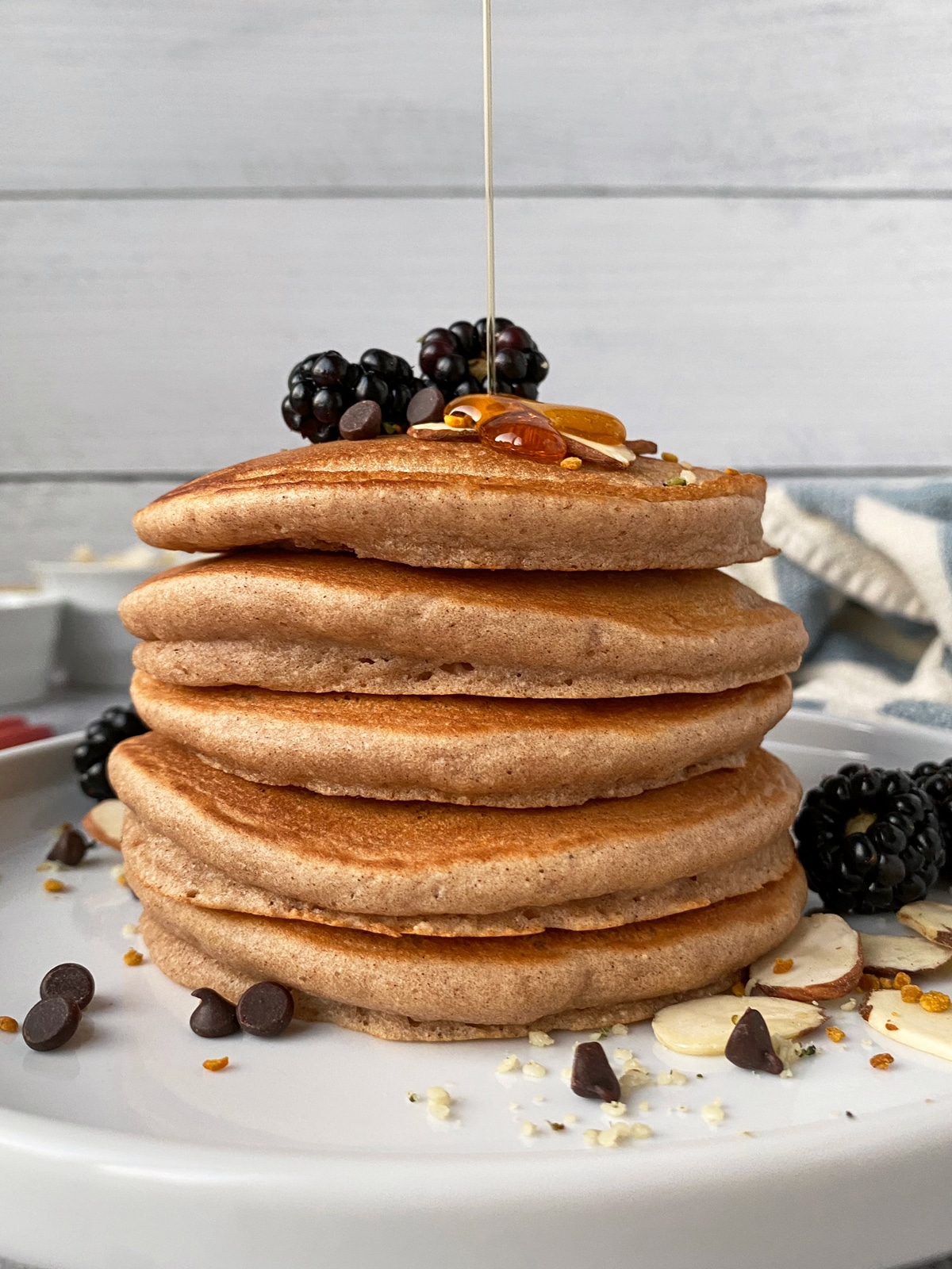 drizzling-maple-syrup-over-a-stack-of-paleo-pancakes