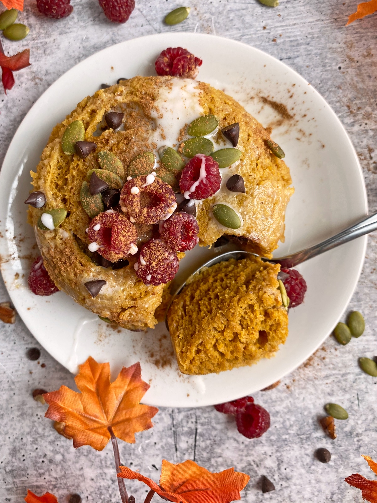 paleo mug cake topped with raspberries, pumpkin seeds and chocolate chips