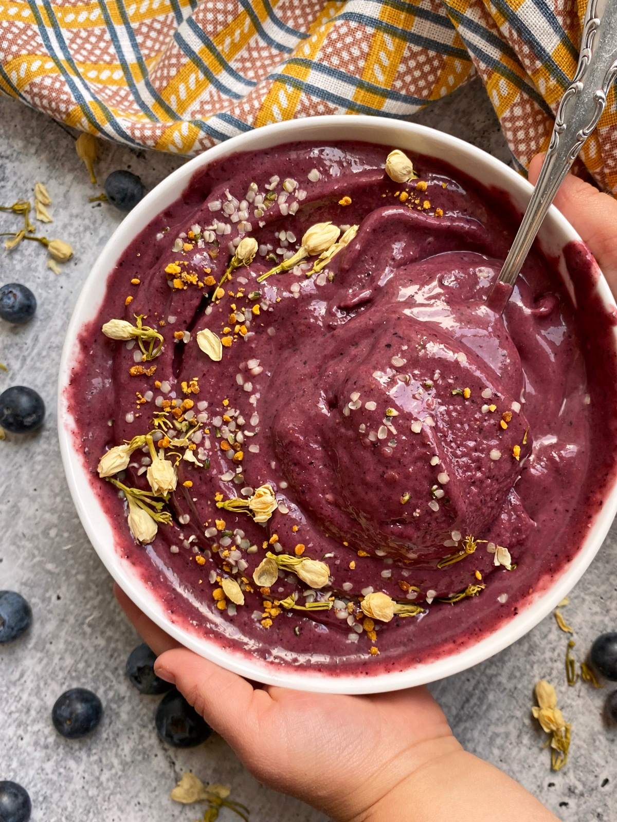 kid hands holding a strawberry blueberry smoothie bowl