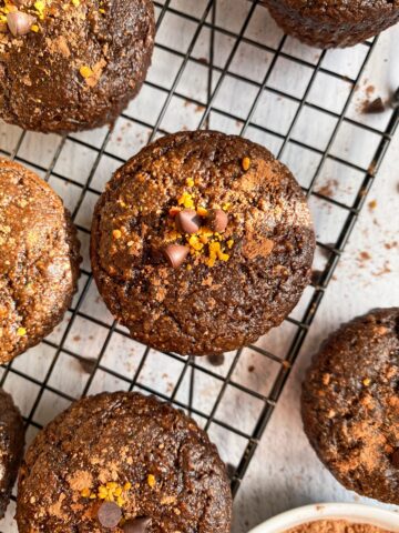 close up of a chocolate zucchini muffin topped with cocoa powder, bee pollen and mini chocolate chips