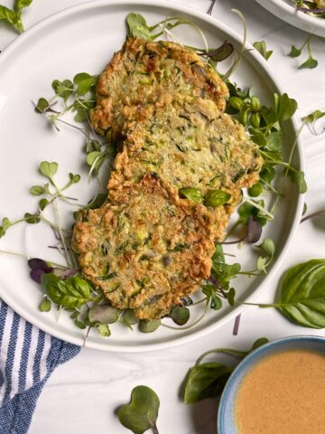 healthy zucchini cakes on plate with microgreens