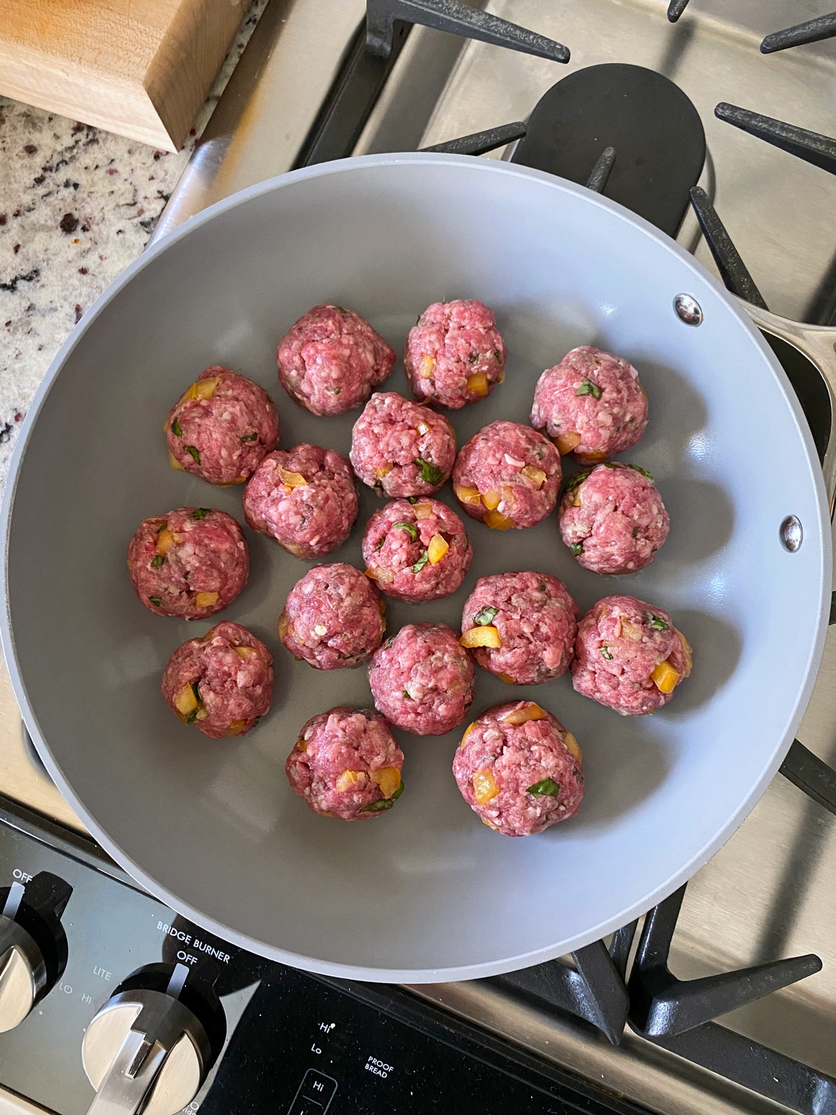 cooking the meatballs on the stove top, in a ceramic pan