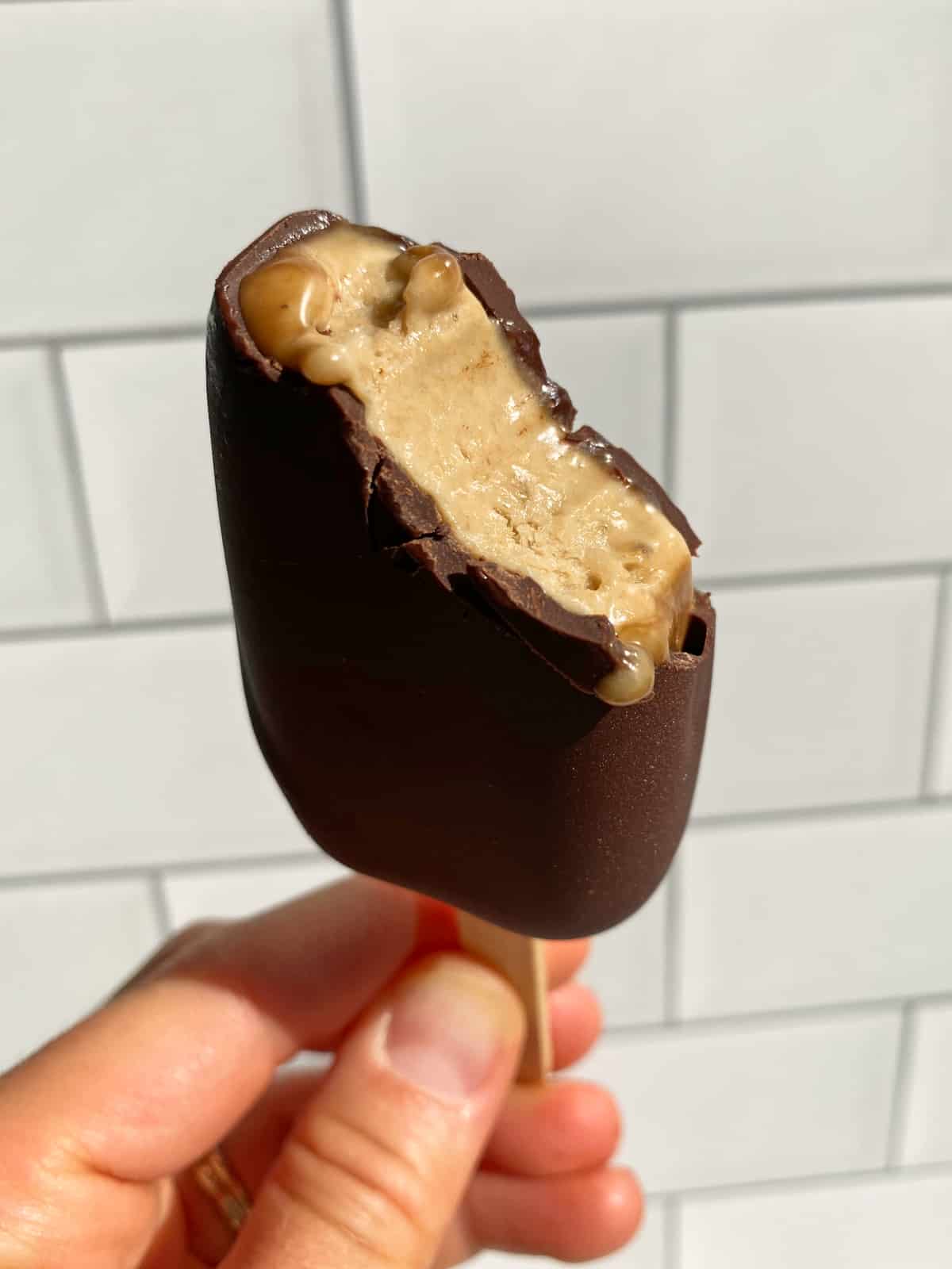 holding an ice cream bar with a bite out of it to show the inside texture