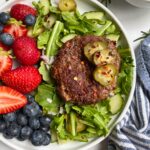 lamb burger on plate with arugula and berries