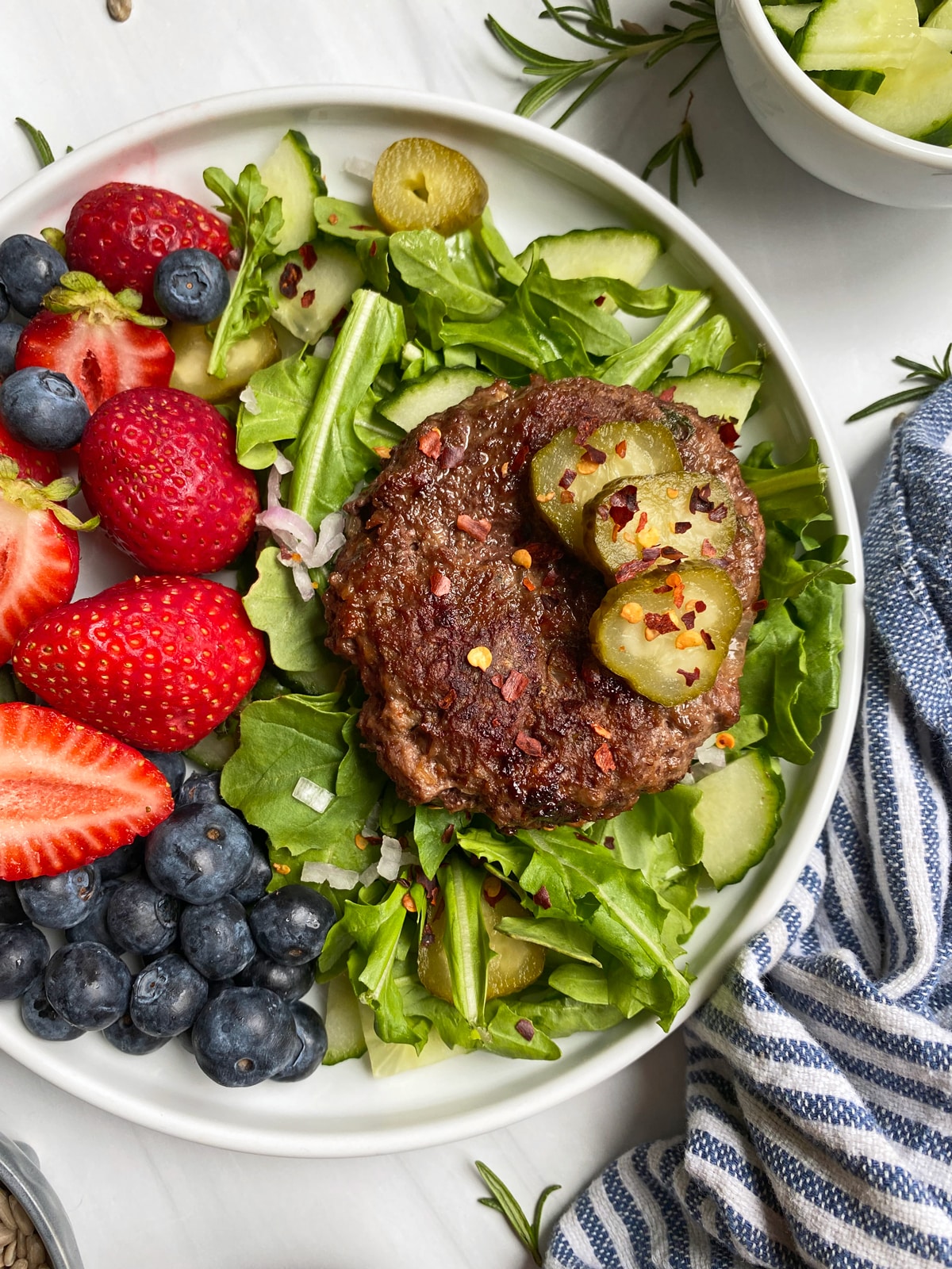 lamb burger on plate with arugula and berries