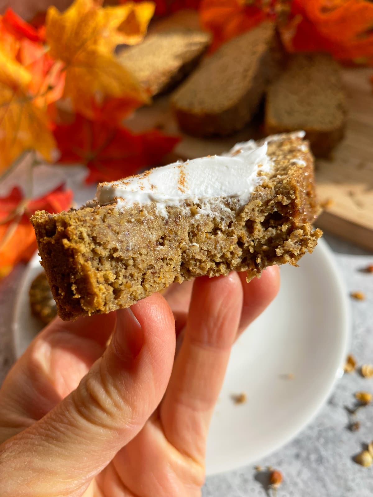 holding a slice of tigernut flour pumpkin bread topped with coconut cream