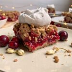 paleo cranberry crumb bar on plate and topped with coconut cream