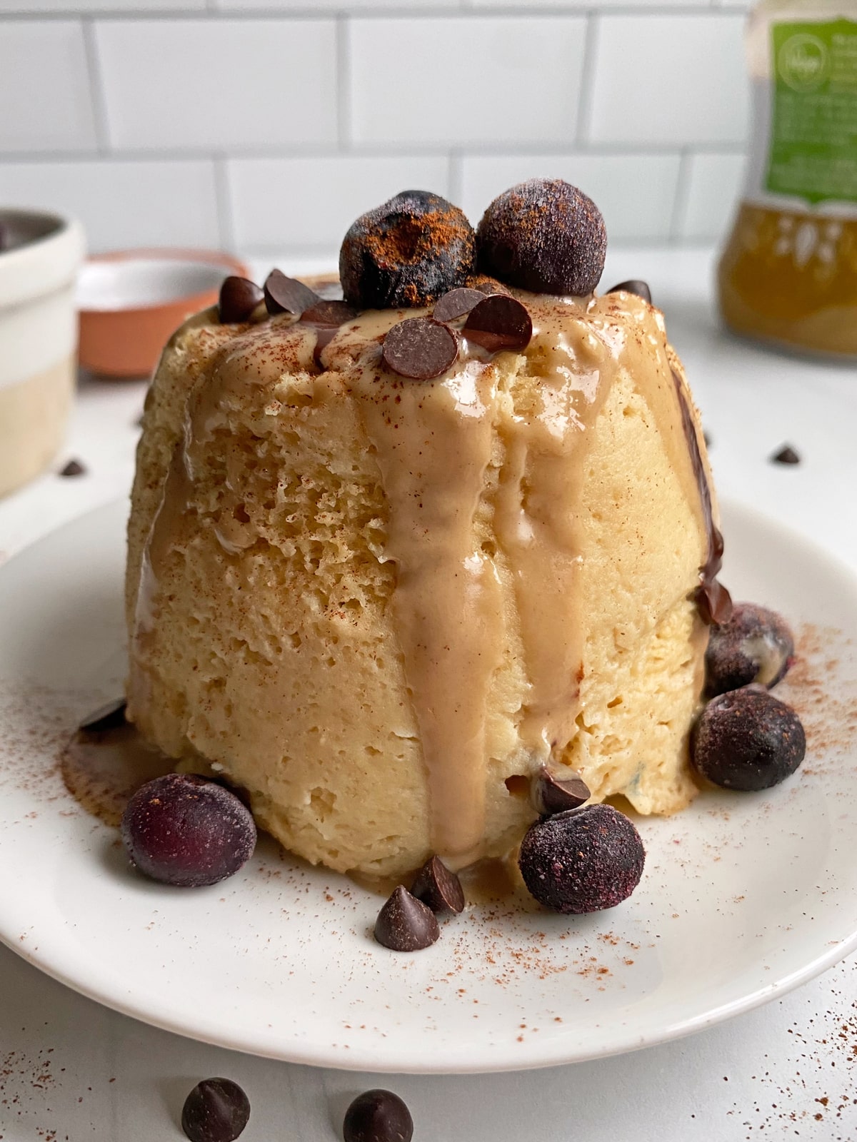 mug cake topped with tahini, dark chocolate chips and frozen blueberries