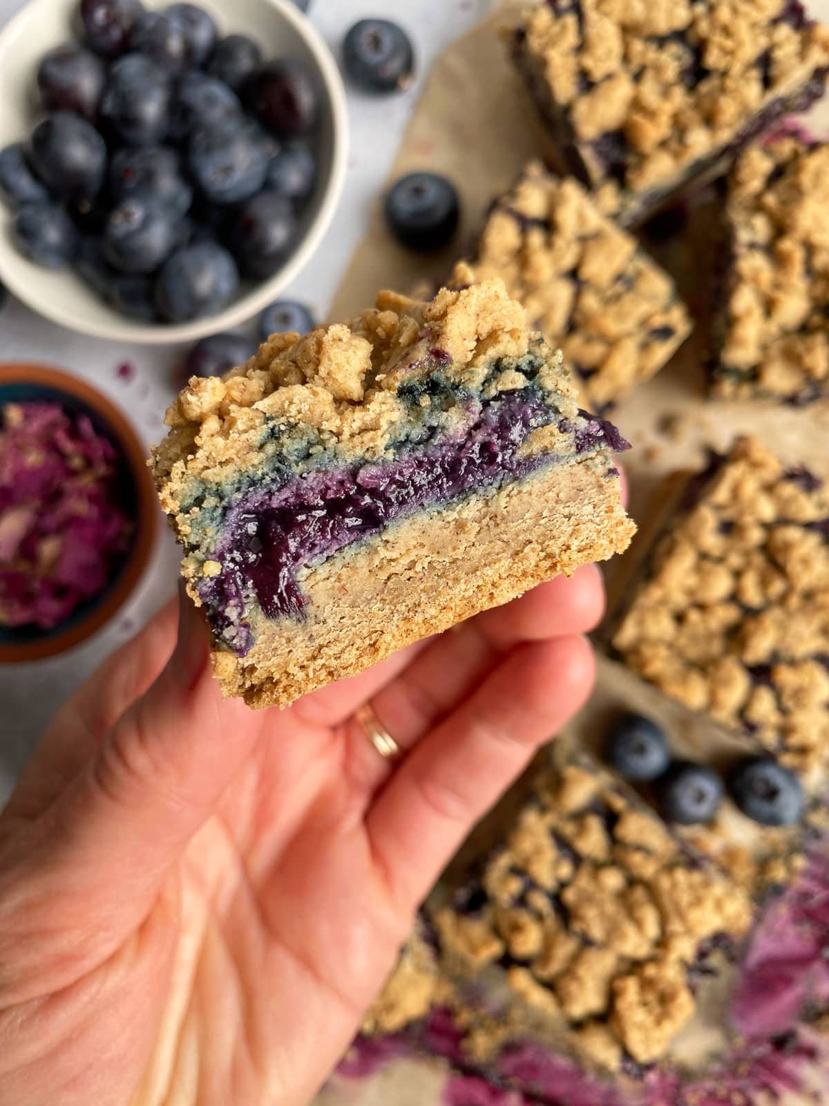 holding a slice of blueberry crumb bar