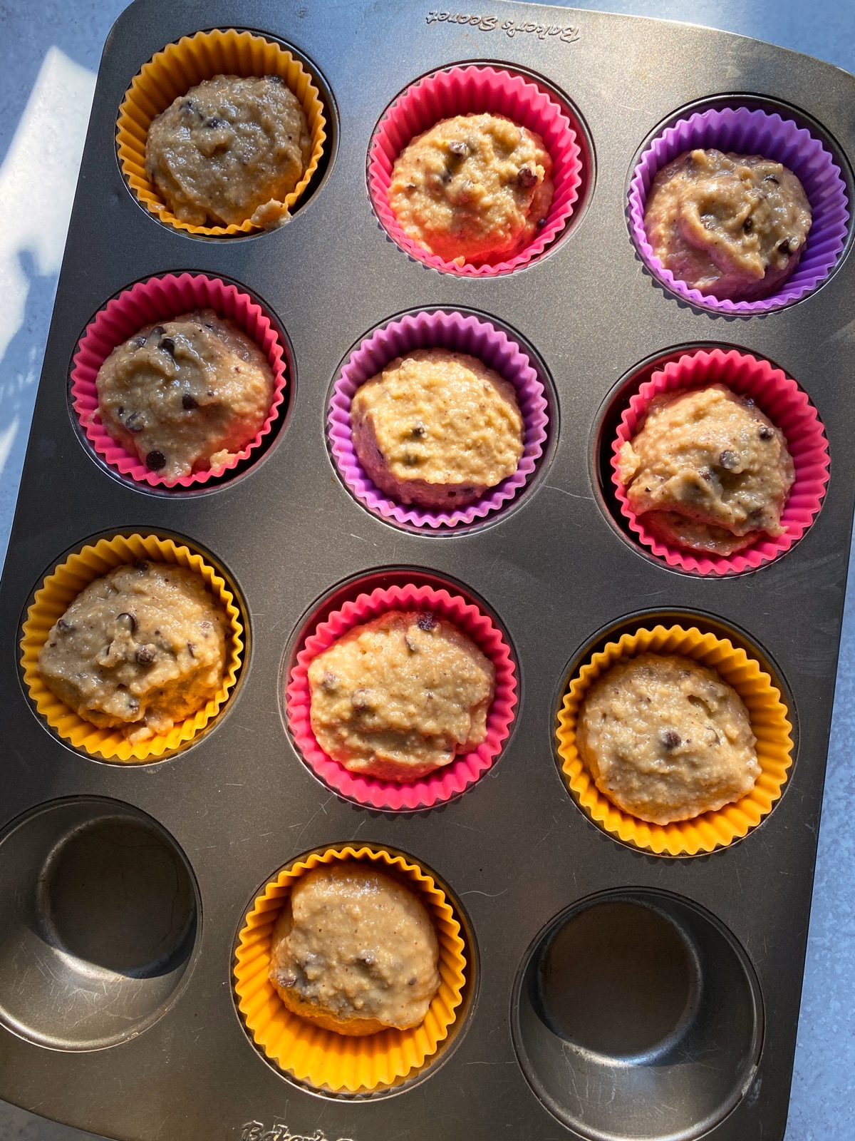 Unbaked plantain muffins in lined muffin tin.