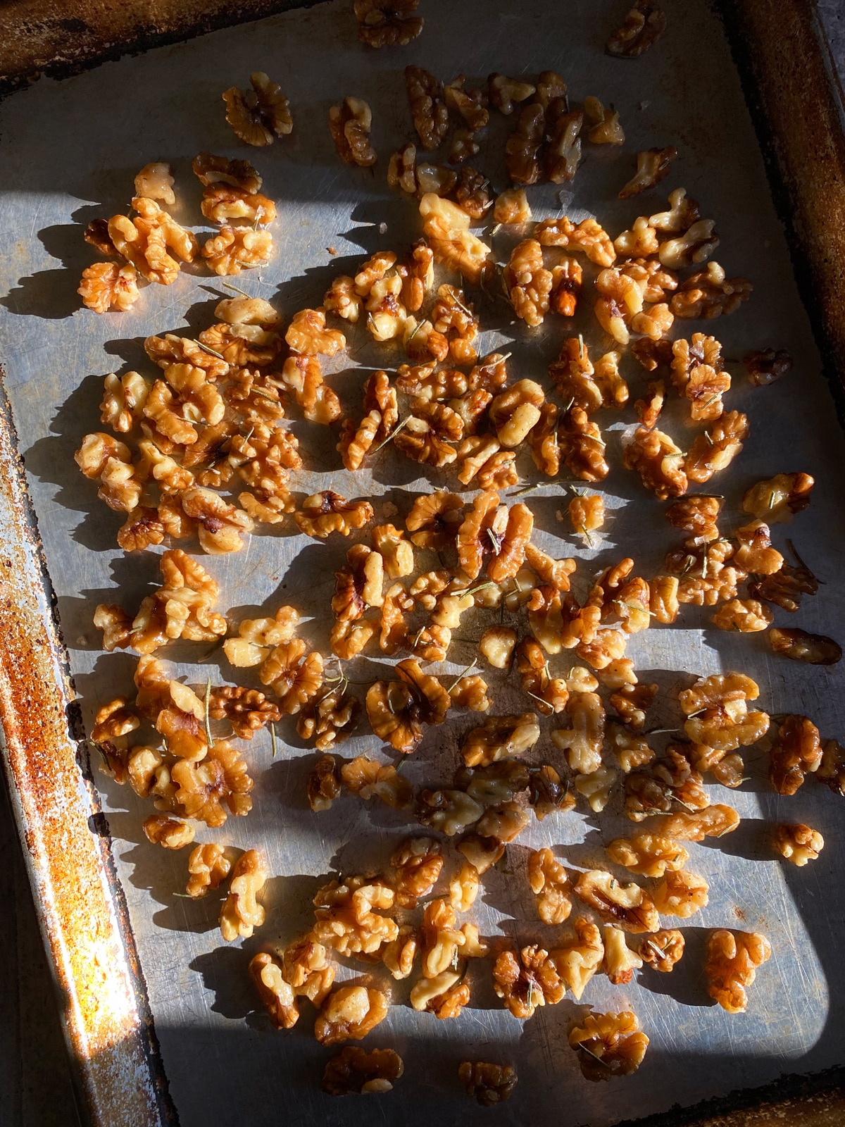 Walnuts spread out on baking sheet, ready for the oven.