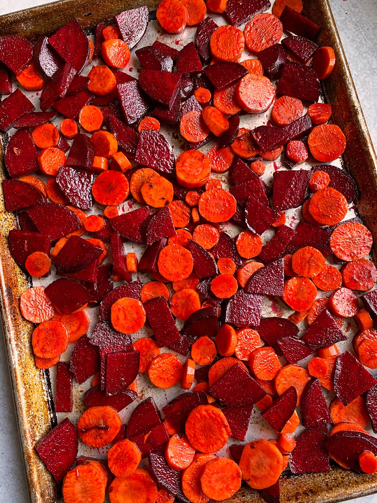 Seasoned beets and carrots on baking sheet.