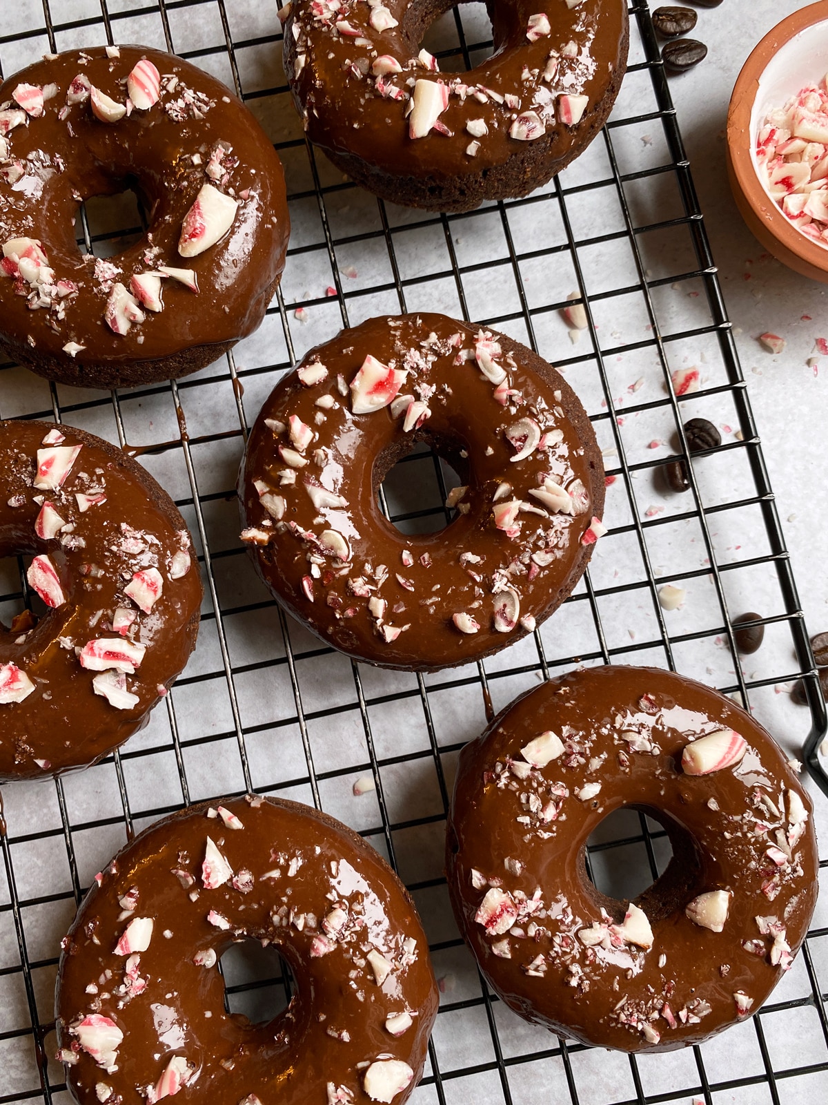 Gluten free peppermint mocha donuts topped with a chocolate glaze and crushed candy canes.