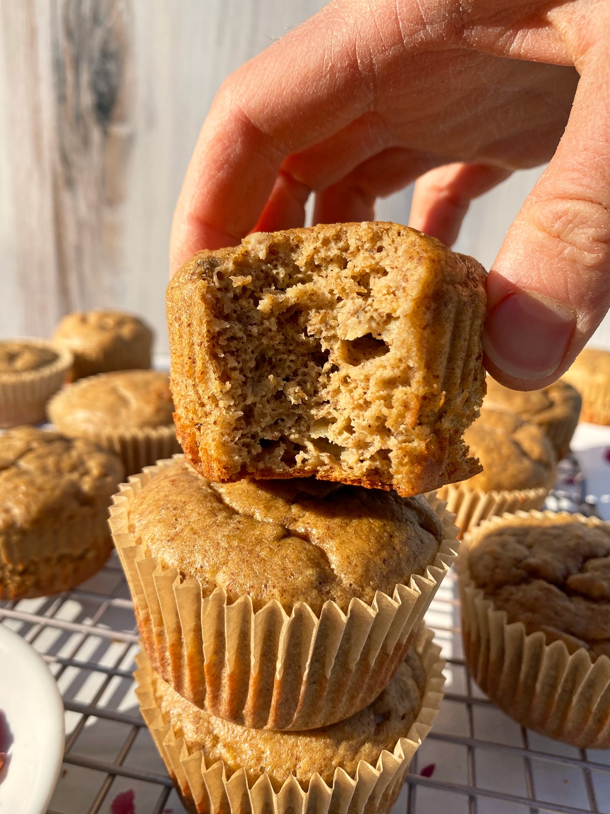 Grabbing a banana protein muffin with a bite out of it to show the inside texture.