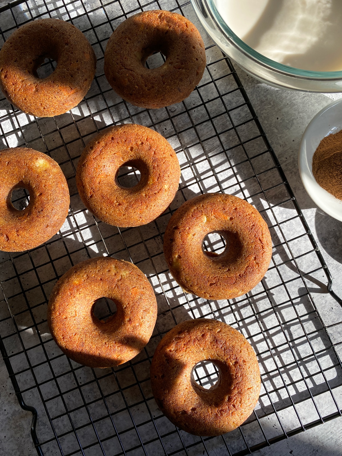 Vegan baked carrot donuts on wire cooling rack.