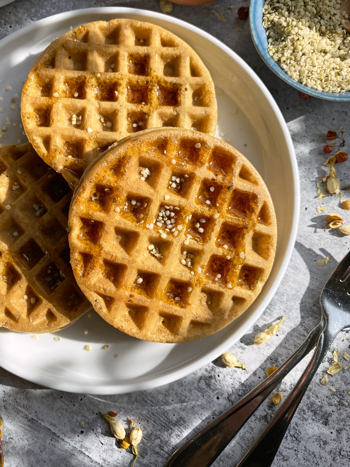 Plate of waffles topped with maple syrup and hemp seeds.