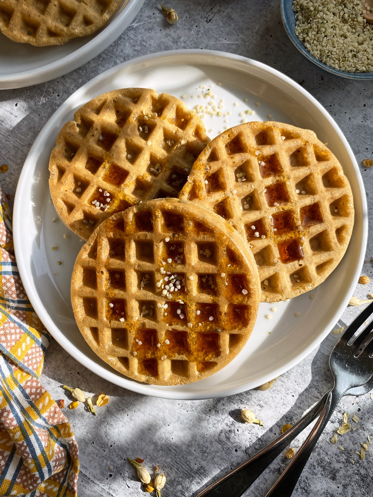 Healthy hemp protein waffles on a plate, topped with maple syrup and hemp seeds.