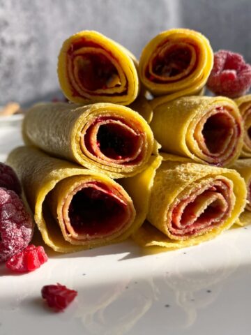 Close up of coconut crepes rolled with raspberry jam.