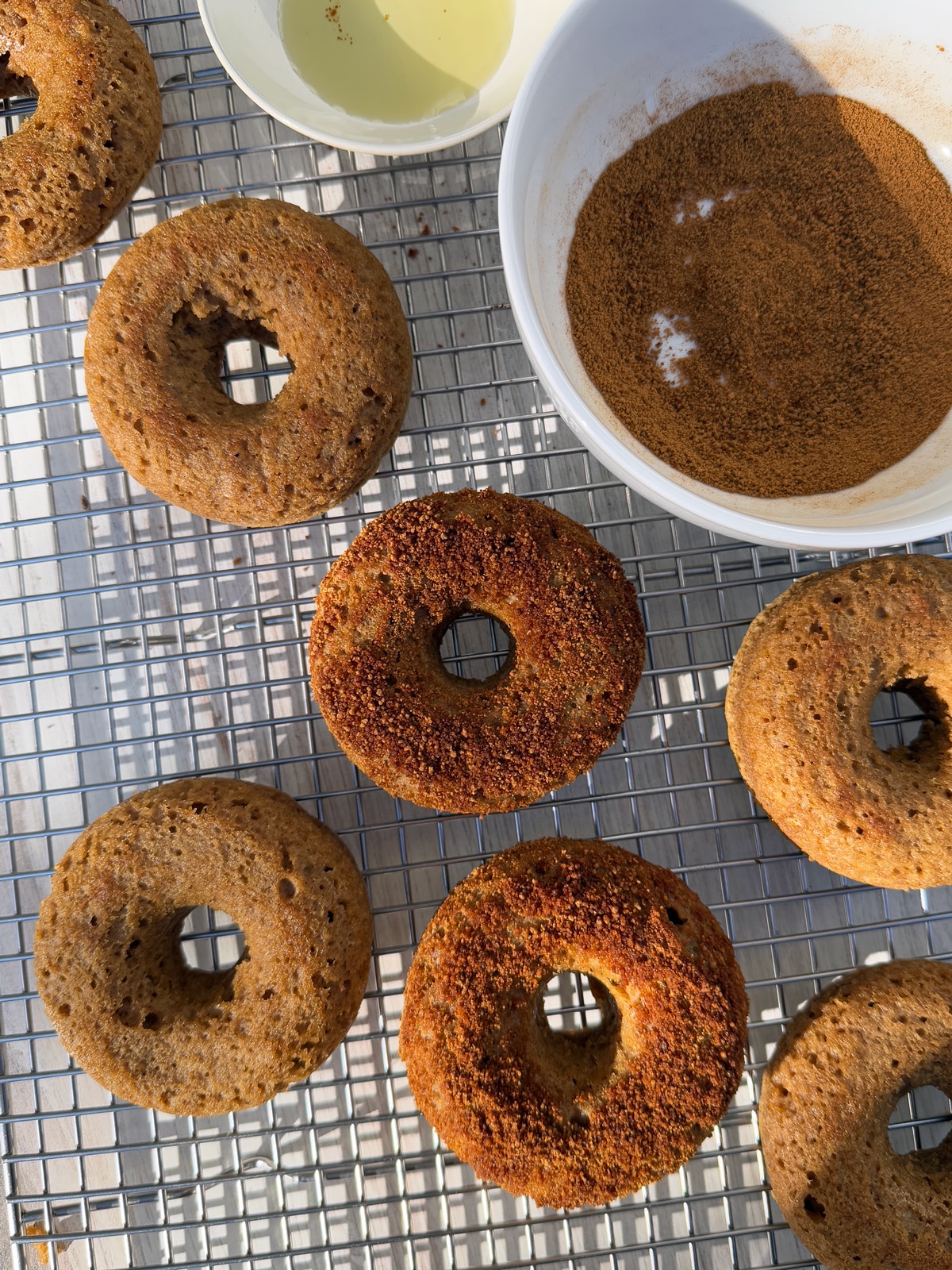 Coating the donuts in cinnamon sugar.