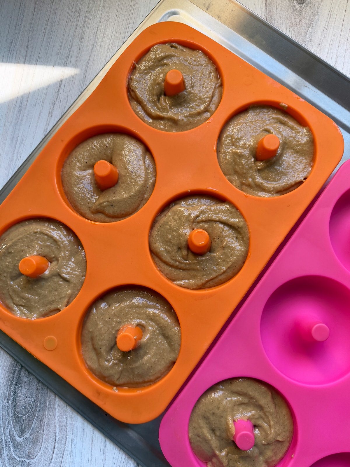 Batter in greased donut pans, ready to bake.