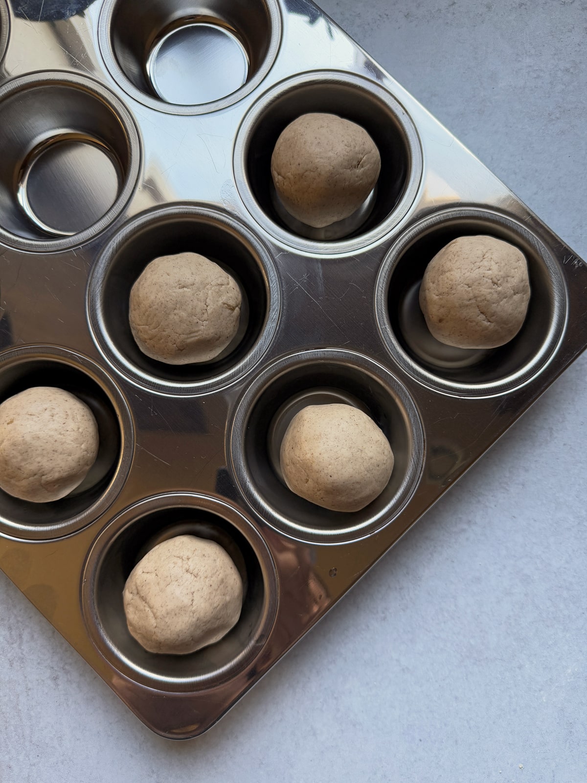 Unbaked rolls in muffin tin.