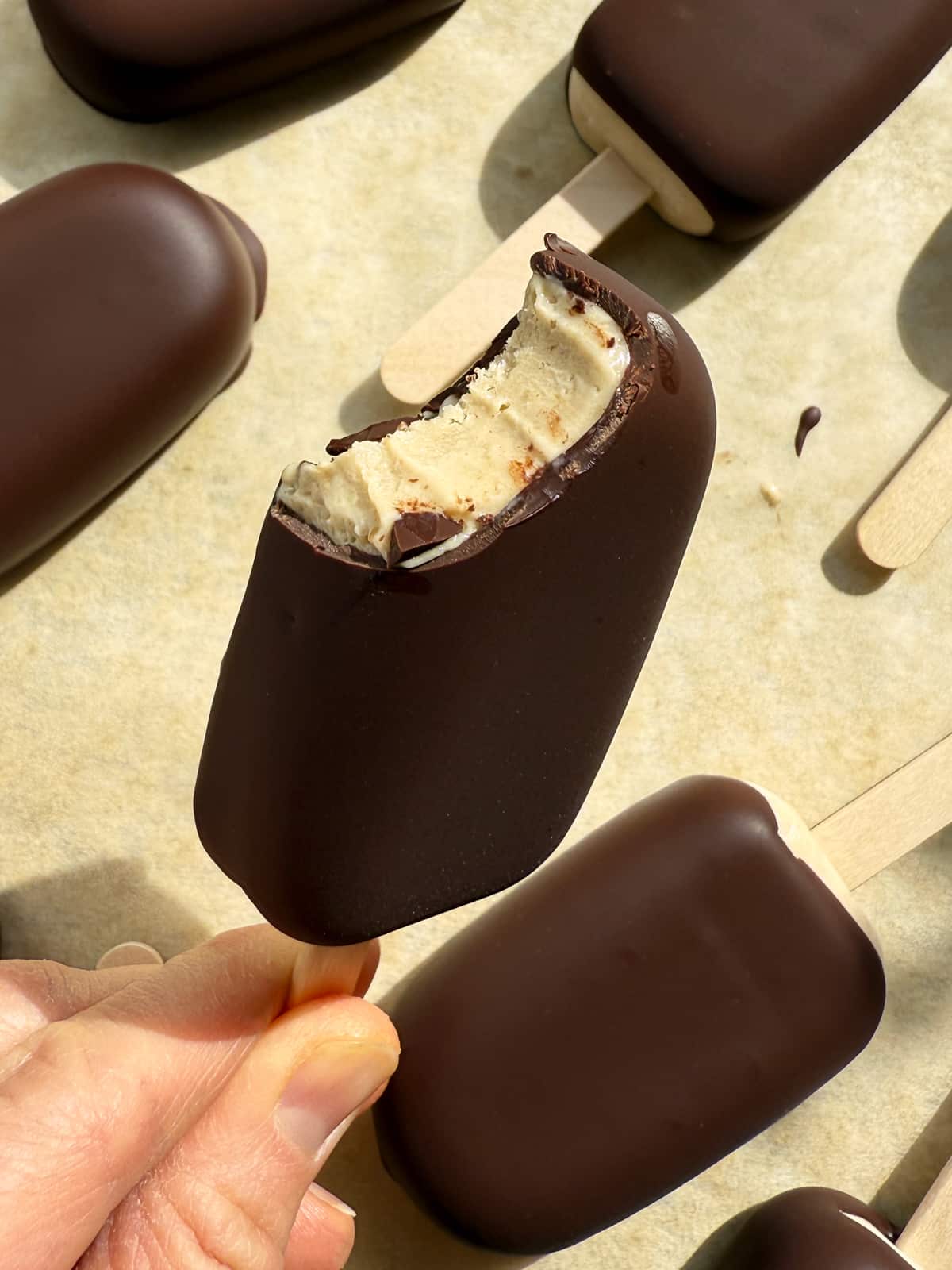 Holding an ice cream bar with a bite out of it.