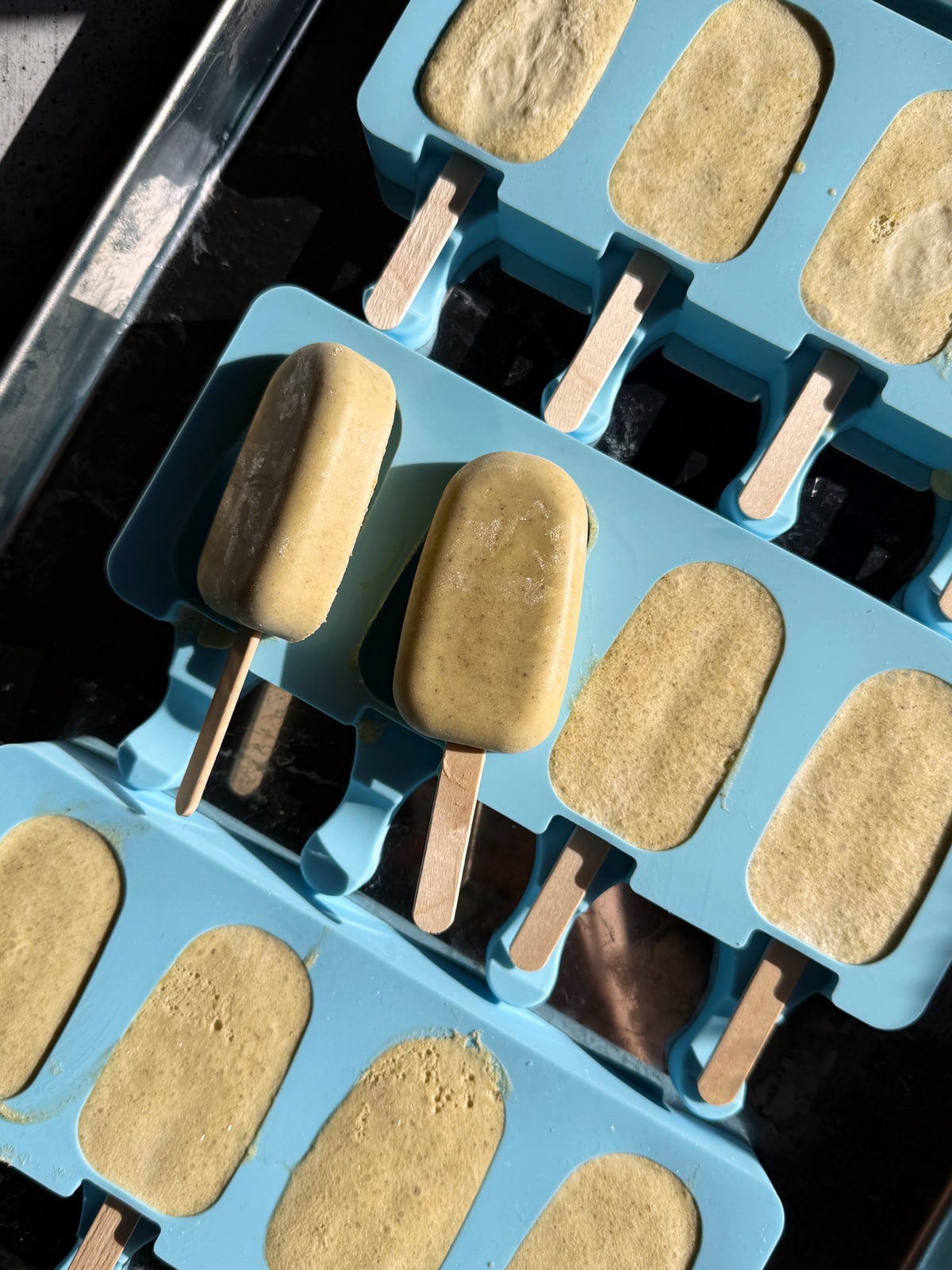Frozen ice cream bars in silicone molds, ready to dip in dark chocolate.