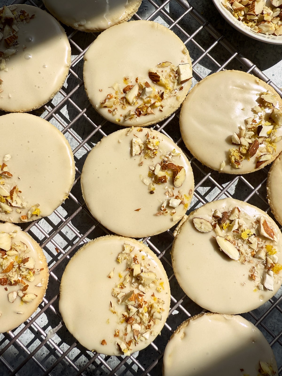 Iced lemon cookies topped with chopped almonds and lemon zest.
