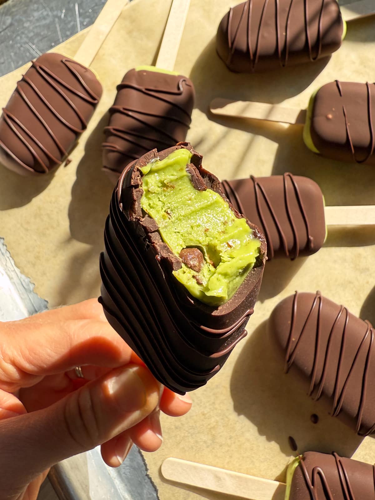 Holding an ice cream bar with a bite out of it.