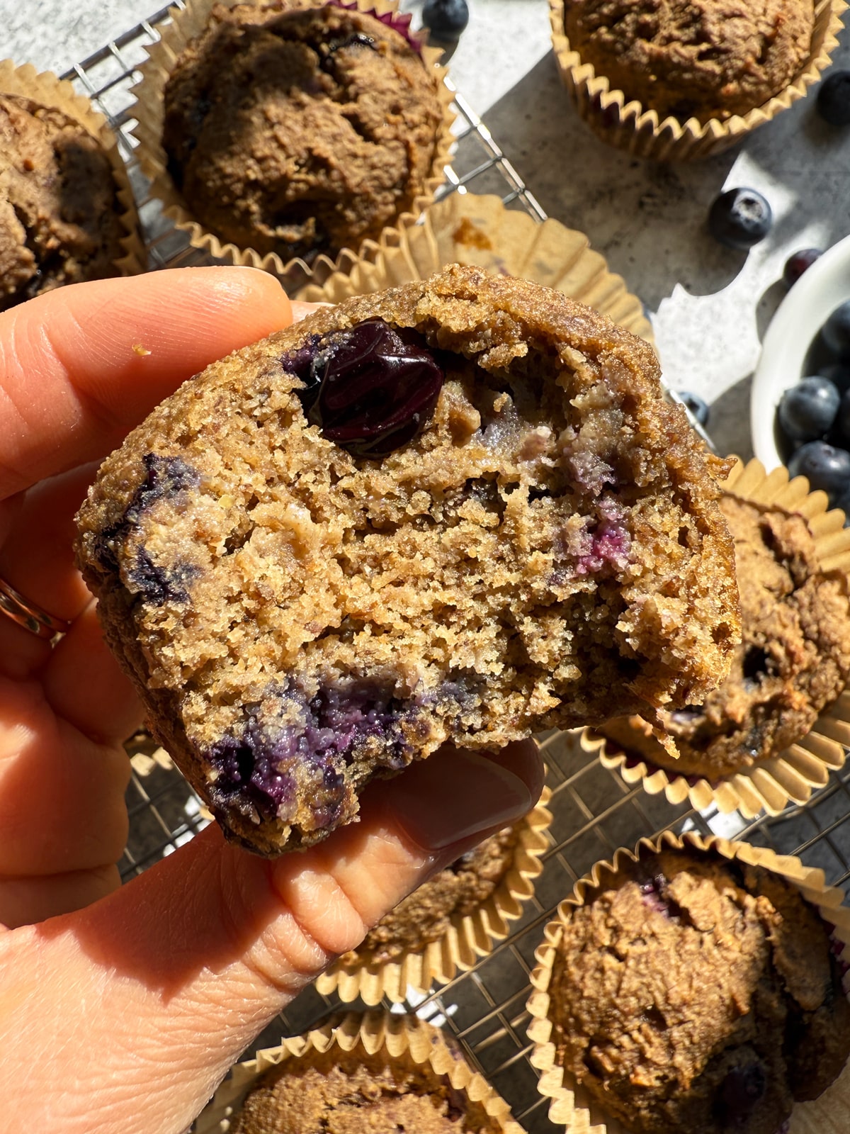 Holding a muffin with a bite out of it.