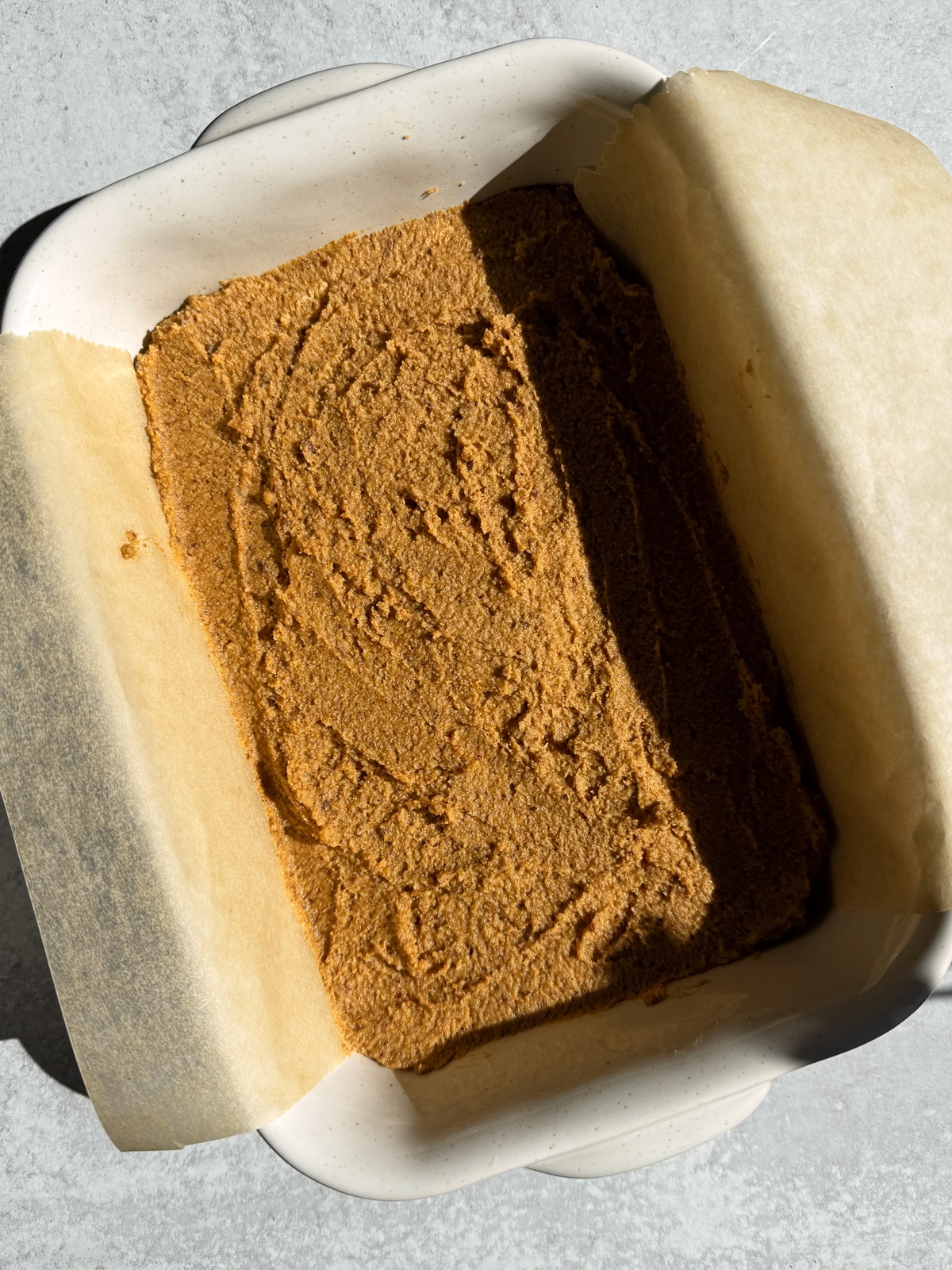 Cake batter in lined baking dish.