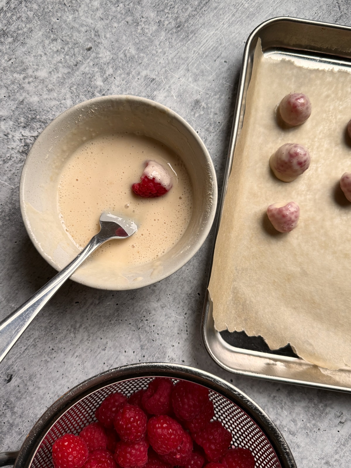 Dipping the raspberries in the protein yogurt mixture.