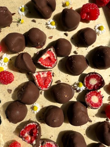 Frozen chocolate covered raspberries on parchment paper.