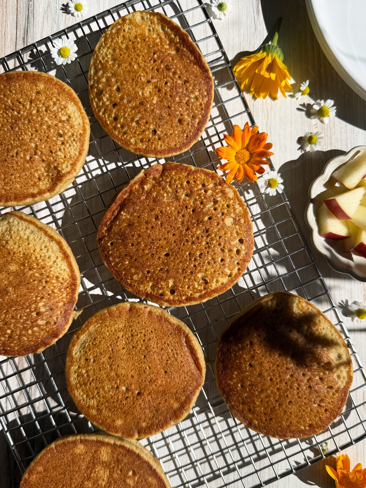 Freshly baked apple banana pancakes on wire cooling rack.