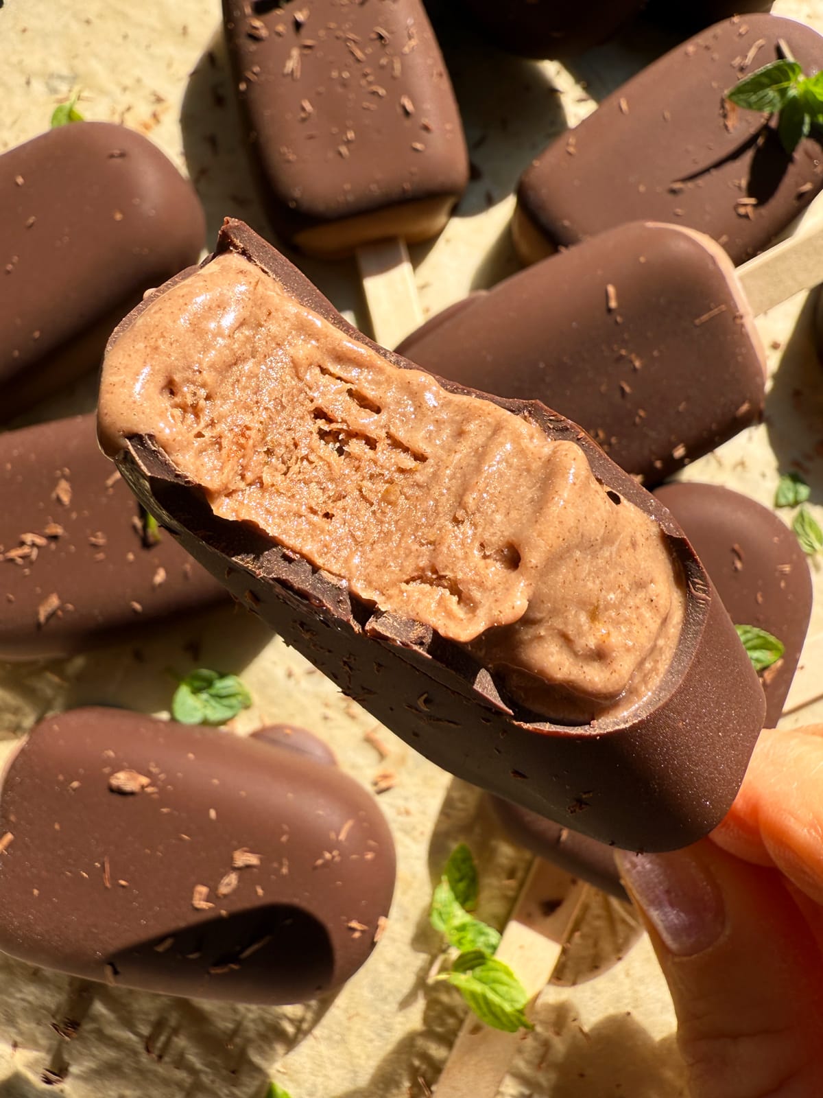 Holding an ice cream bar with a bite out of it to show the inside texture.