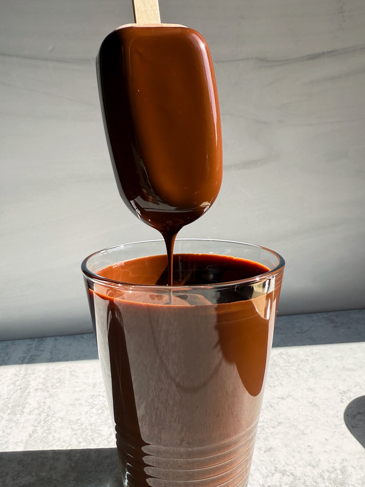 Dipping a bar in melted chocolate and coconut oil.