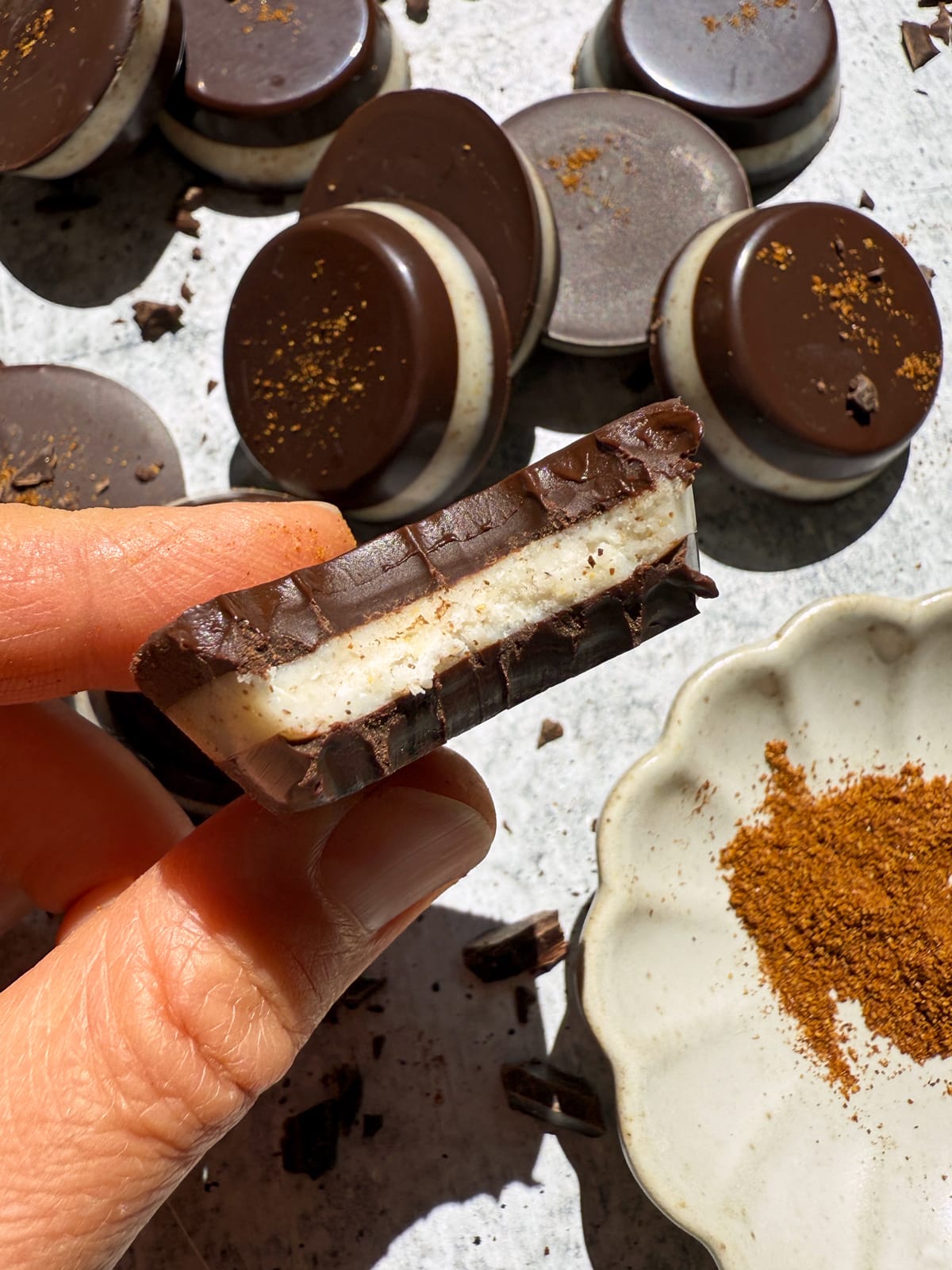 Holding a coconut butter cup with a bite out of it.