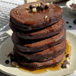 Stack of 5 pancakes drizzle with maple syrup.