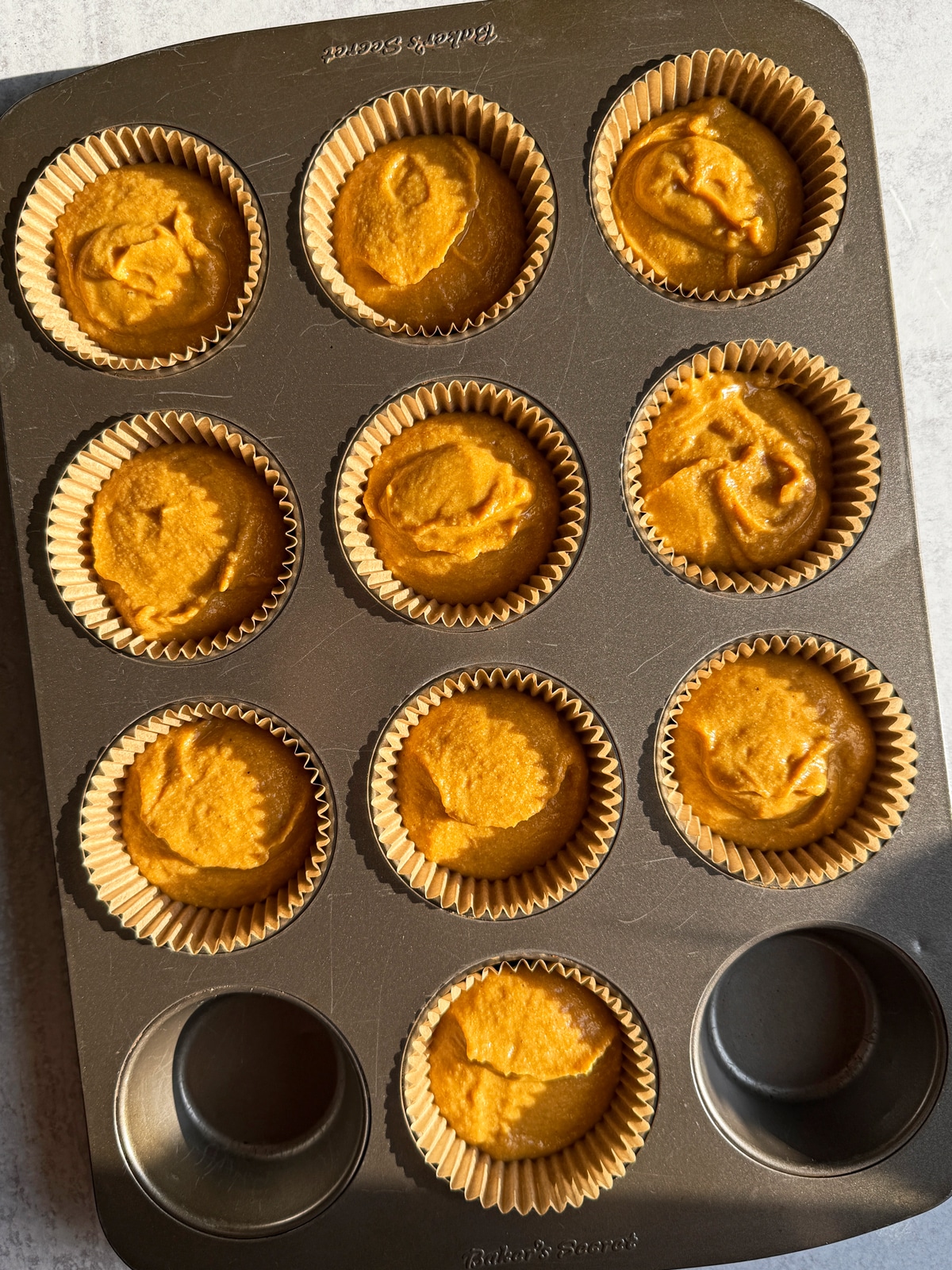 Muffin batter in lined muffin pan.
