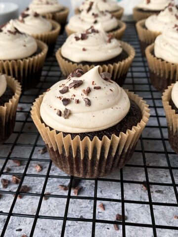 Frosted and decorated chocolate cupcakes on wire cooling rack.
