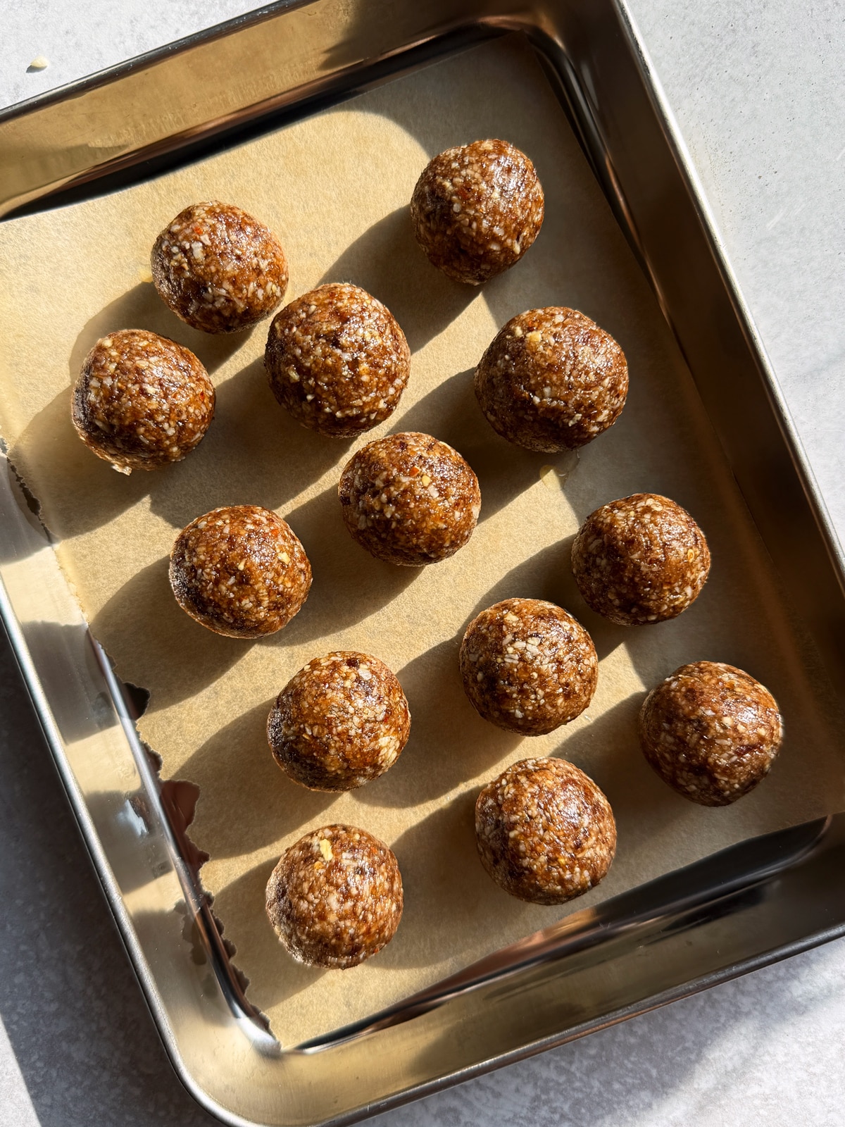 Rolled balls on lined baking sheet.