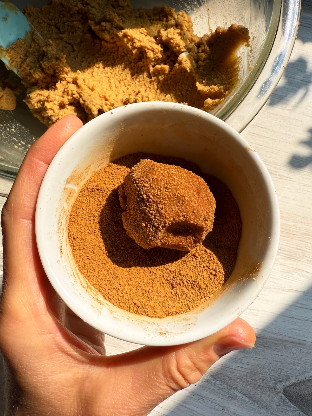 Rolling cookie dough in cinnamon sugar.