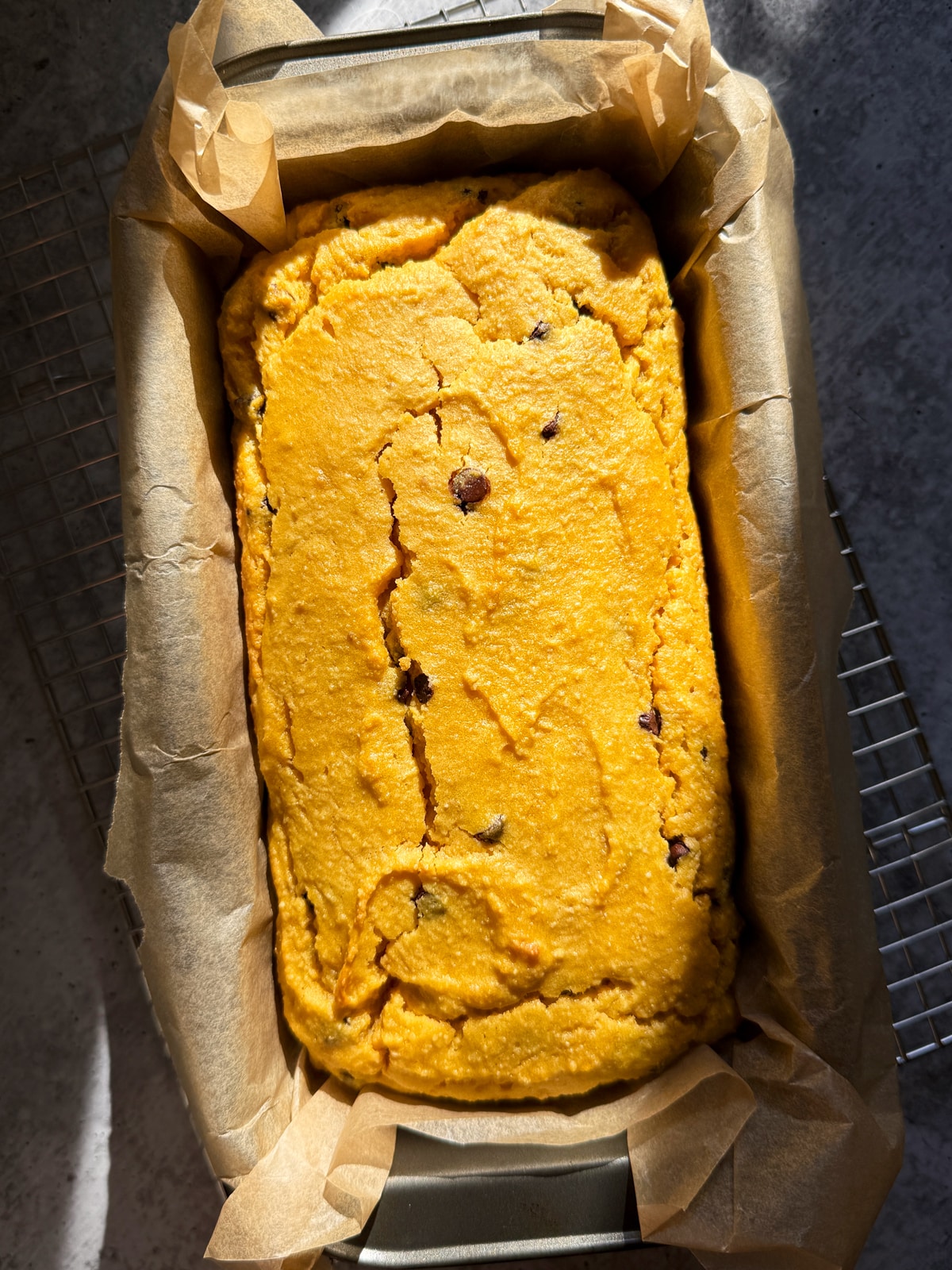 Baked squash bread cooling in lined loaf pan.
