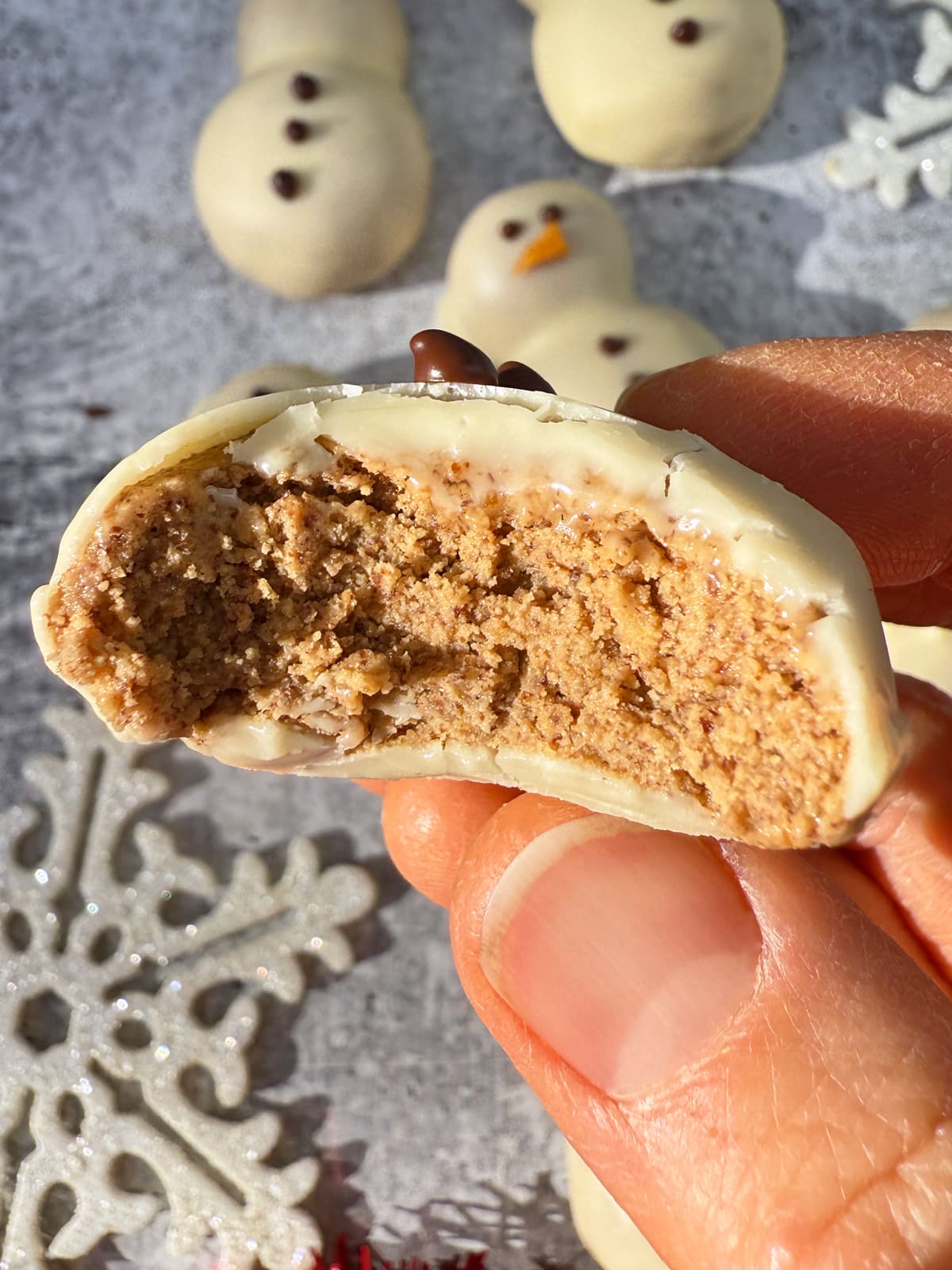 Holding a snowman protein ball with a bite out of it.