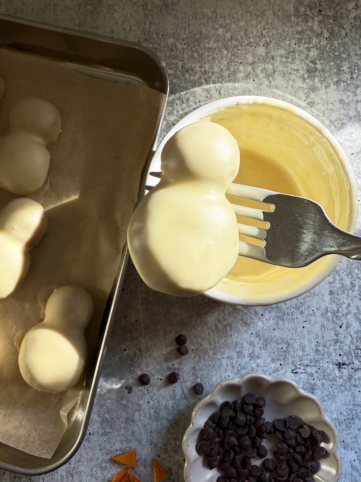 Dipping the snowman filling in melted white chocolate.