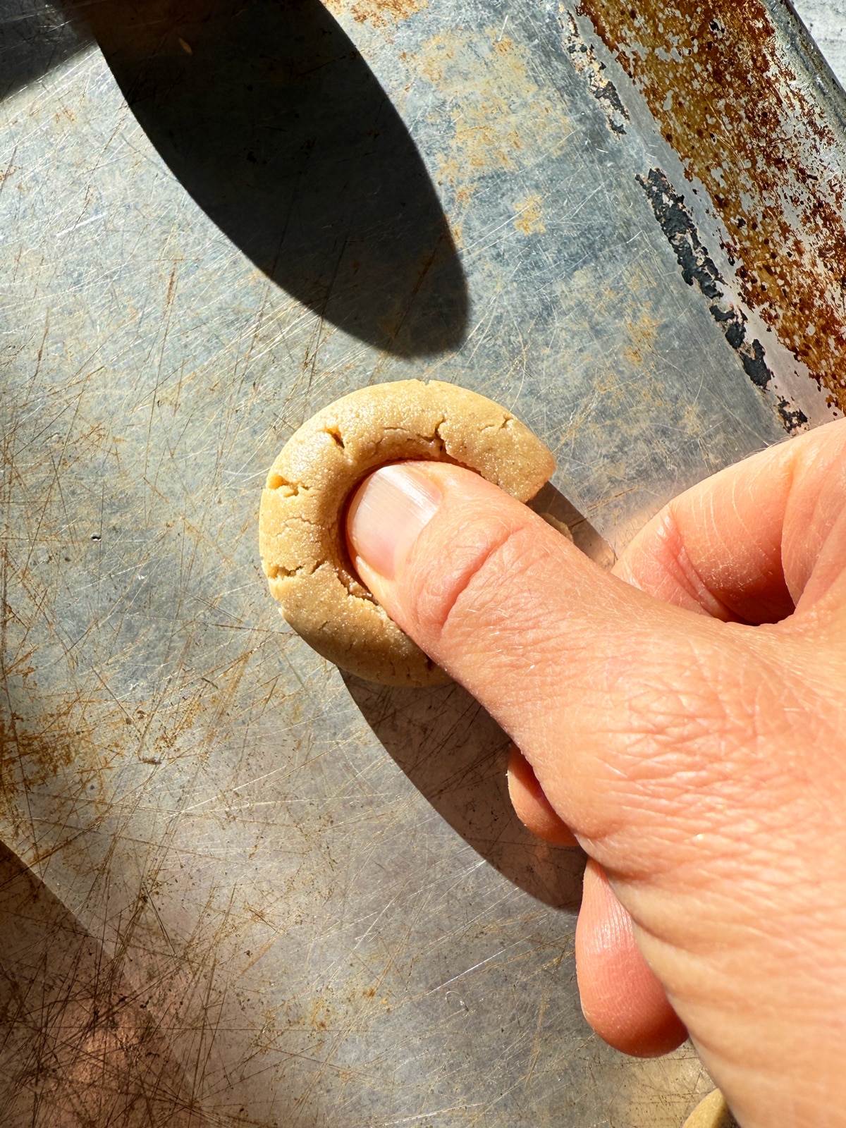 Pressing my thumb into the cookie to create an indent.