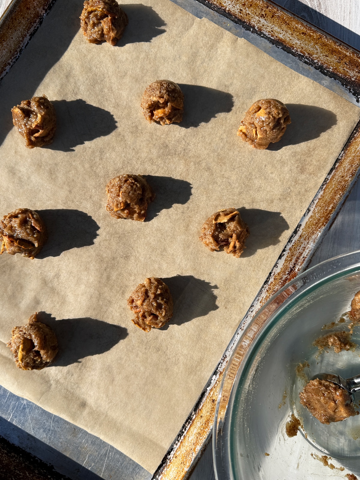 Scooping the cookie dough onto a lined baking sheet.
