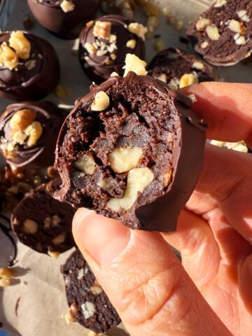 Holding a truffle with a bite out of it to show the inside texture.