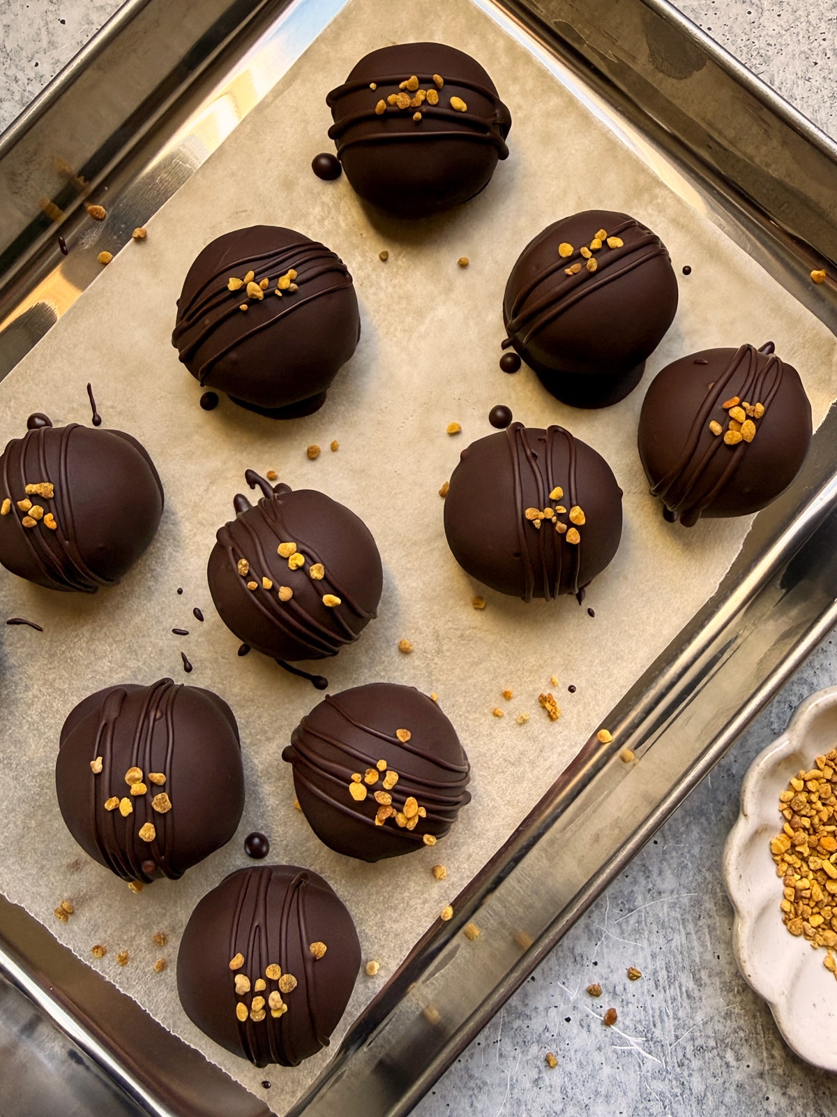 Protein balls decorated with a drizzle of chocolate and bee pollen.