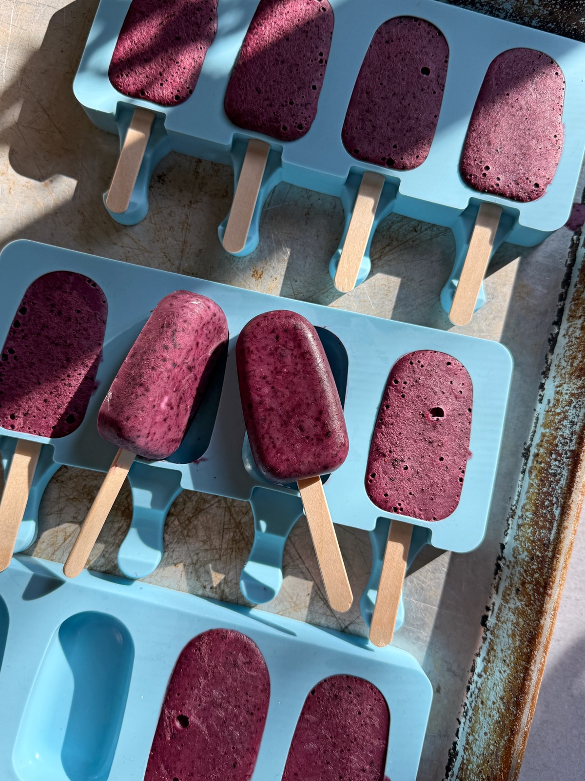 Frozen blueberry yogurt bars in silicone popsicle molds.